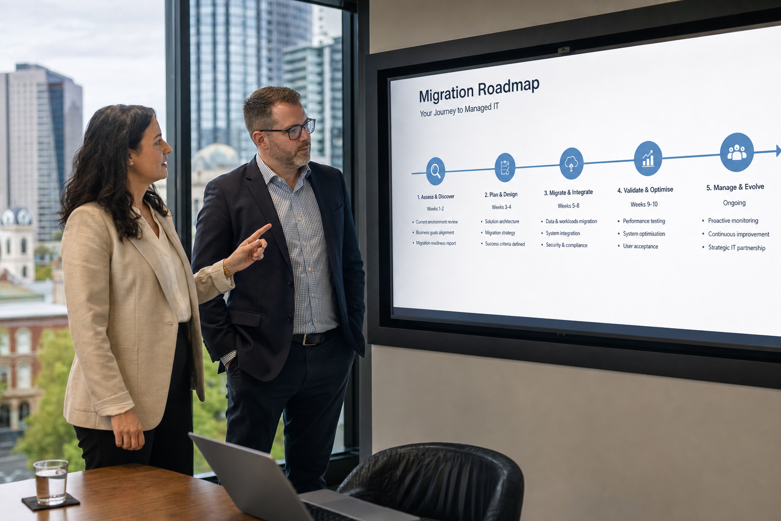 An Adelaide internal IT manager and managed services partner reviewing a migration roadmap on a large screen in a modern meeting room.